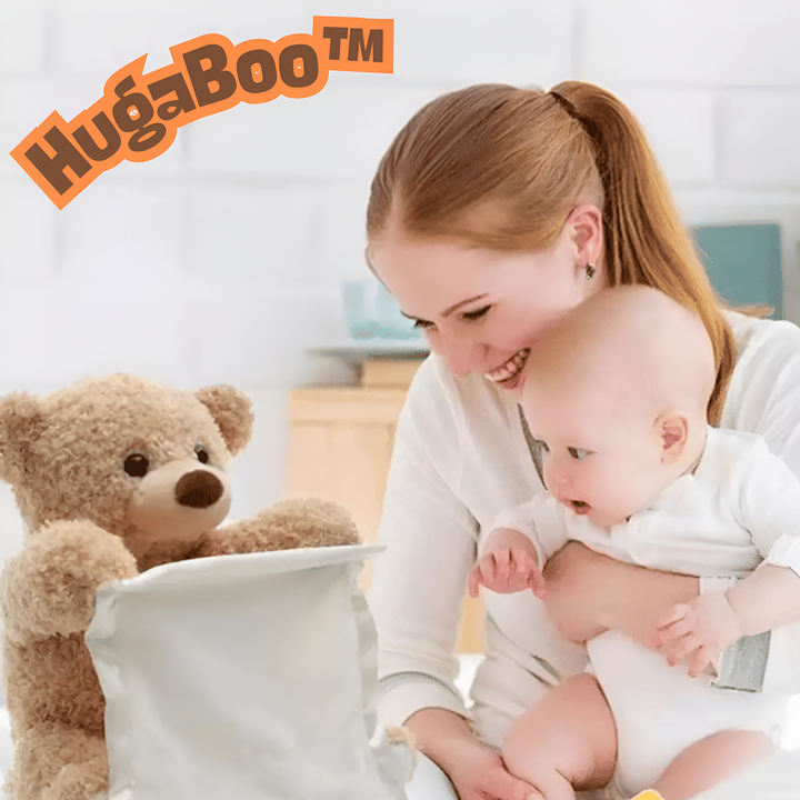 En smilende kvinde holder en baby, som kigger på en lysebrun plysbjørn, der titter frem over et lyst stofstykke. 1