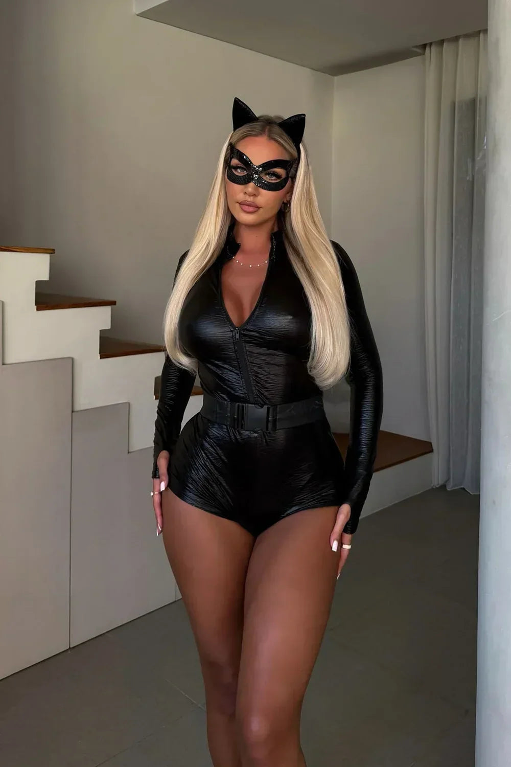 Model med langt lyst hår står ved en trappe iført bodysuit, bælte, katteører og palietmaske 6