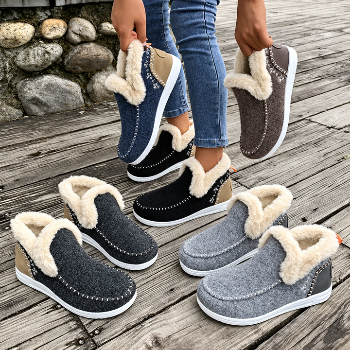 Flere par sneakers med plysfor i blå, brun, sort, mørkegrå og lysegrå stillet sammen på en trægulv-terrasse. 6