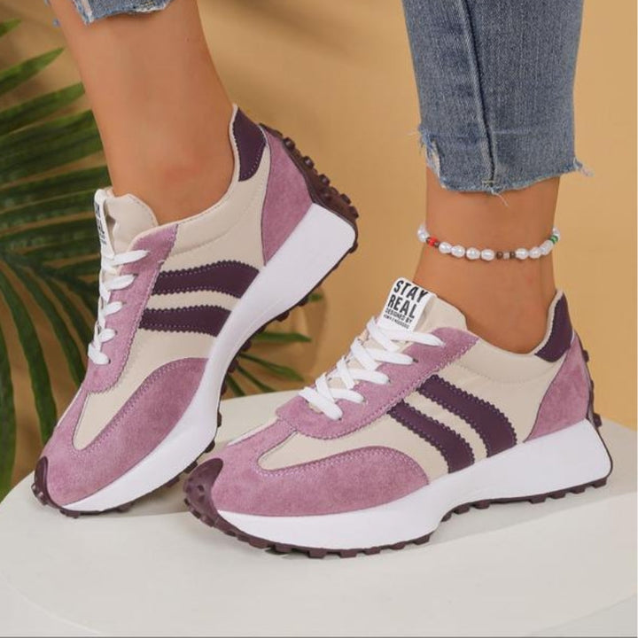 Lilla og beige sneakers med mørklilla striber og tyk hvid sål båret af en model på hvid sokkel 12