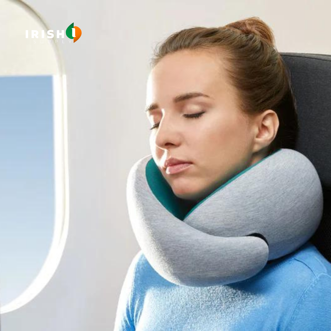 Kvinde med lukkede øjne sover på et flysæde med en grå nakkepude, der støtter hage og nakke, ved vinduet. 1