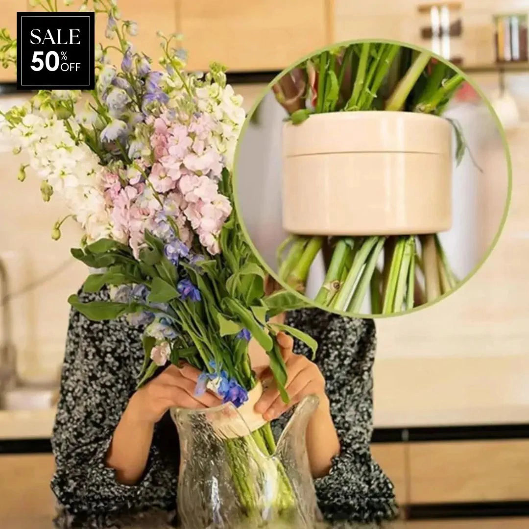 Person holder en stor buket med lyserøde, hvide og blå blomster over en glasvase, med forstørret udsnit af den cremefarvede indsats. 1