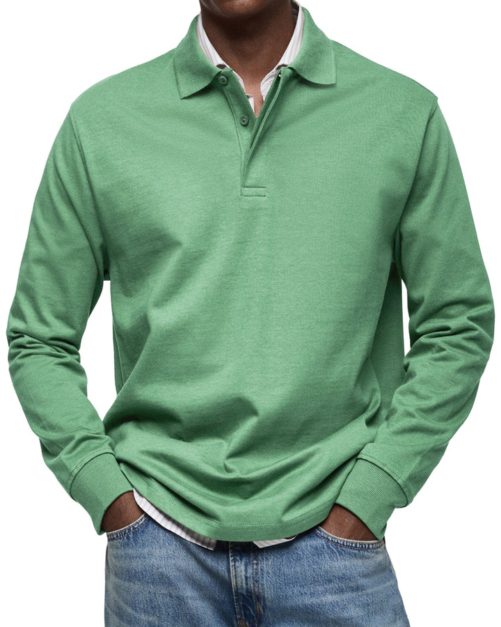Langærmet poloshirt i grøn, båret af en model med stribet skjorte under og jeans, set forfra. 7