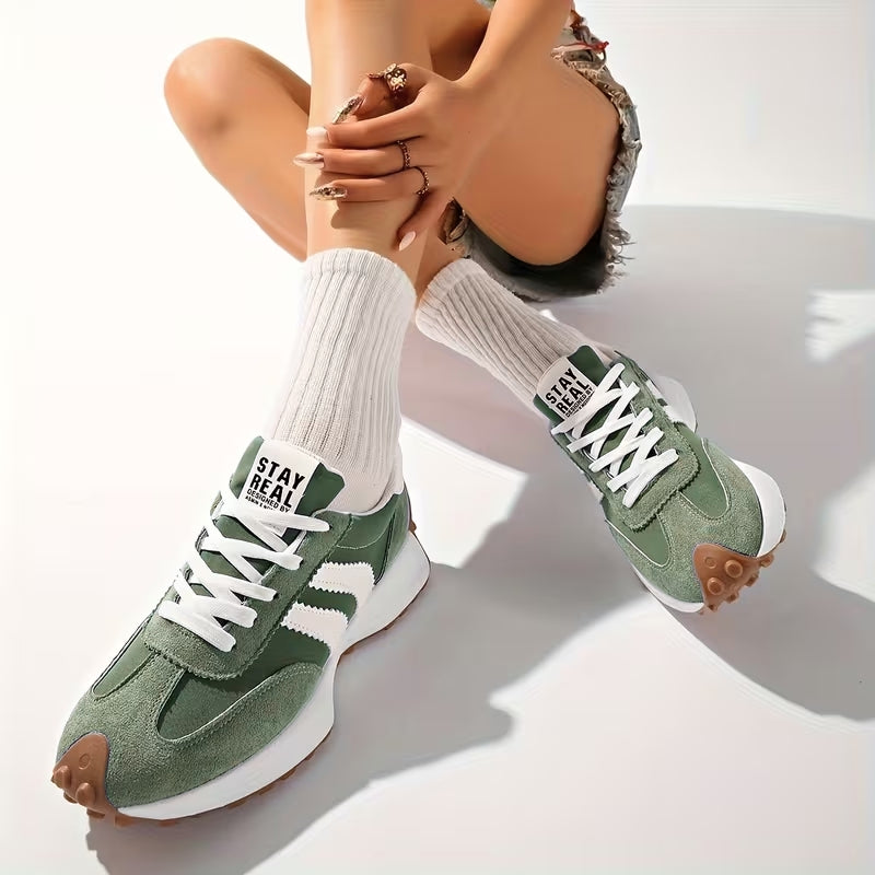 Model i hvide ribstrikkede sokker og grønne ruskindssneakers, siddende med krydsede ben på hvidt underlag 7