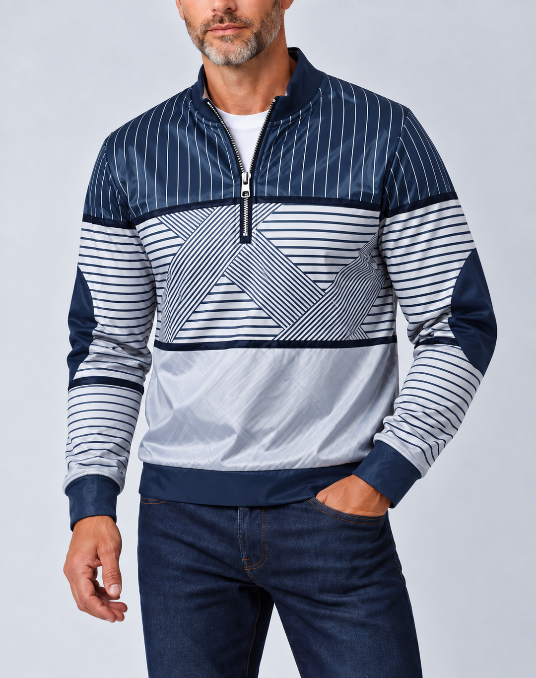 Mand med gråt skæg i marineblå og hvid stribet pullover med halv lynlås, hånden i lommen på mørke jeans. 1