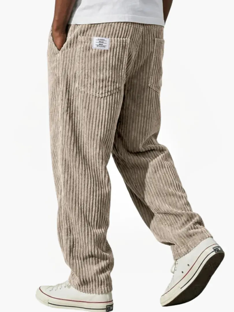 Model set bagfra i beige fløjlsbukser med afslappet pasform, baglommer og lille mærke ved linningen, med hvide sneakers. 3