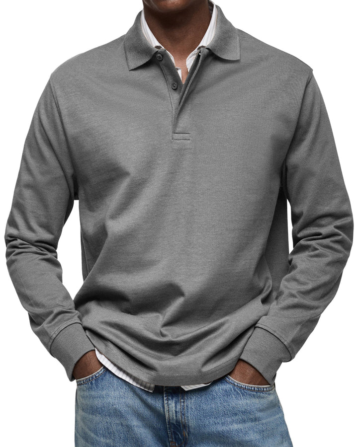 Langærmet poloshirt i mellemgrå, båret af en model med stribet skjorte under og jeans, set forfra. 6