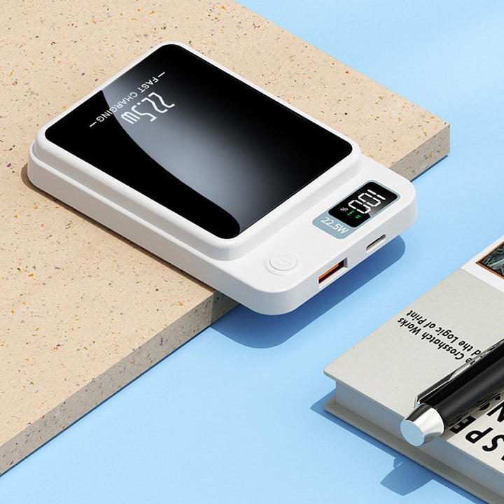 Hvid powerbank liggende fladt på en overflade, med USB-udgang, USB-C-port, tændknap og digitalt display synlige. 6