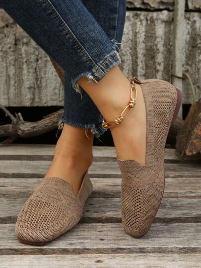 Brune mesh slip-on sko på model med krydsede ben, der viser sideprofil og den firkantede tå. 6