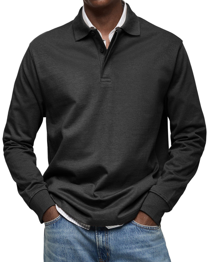 Langærmet poloshirt i sort, båret af en model med stribet skjorte under og jeans, set forfra. 4