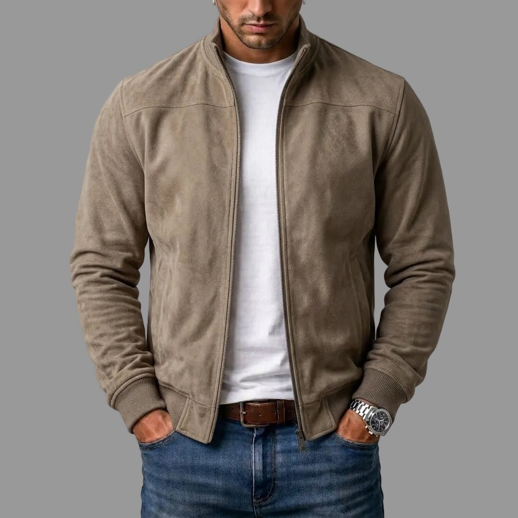 Model i sandfarvet jakke i ruskindslook med åben lynlås og ribmanchetter, båret over hvid t-shirt og jeans. 2
