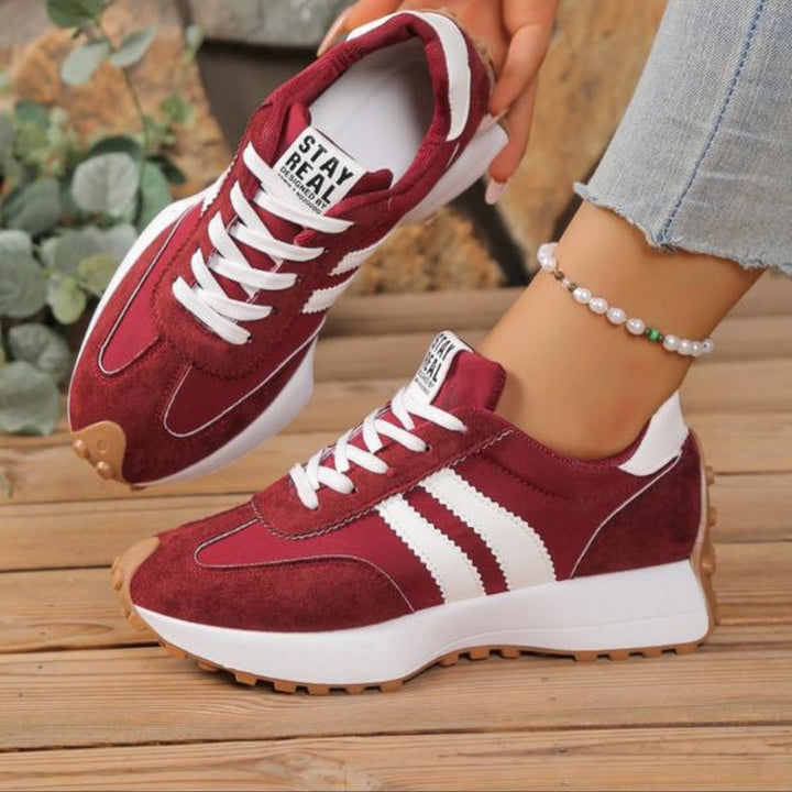 Bordeaux sneakers med hvide striber og snørebånd båret af en model, med perlearmbånd om anklen 4