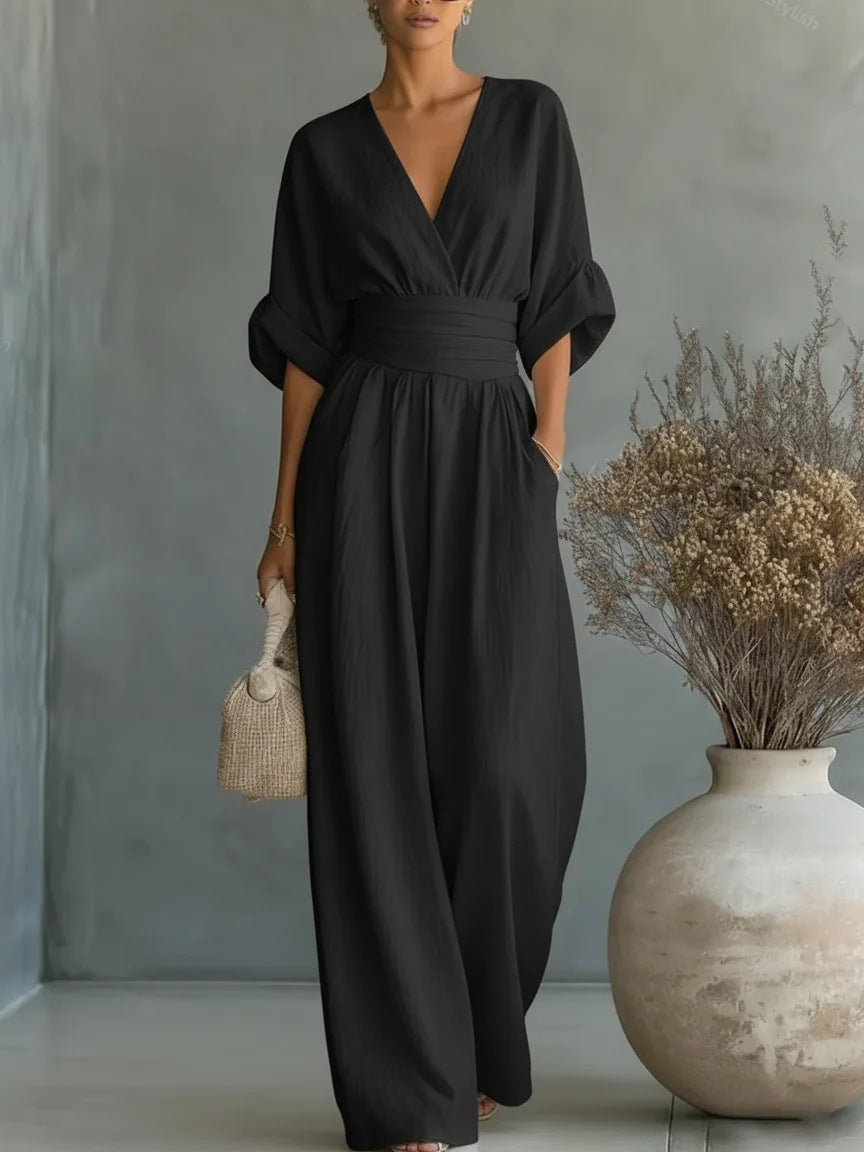 Jumpsuit i sort set forfra på model med V-udskæring, vide ben og strikket håndtaske 5