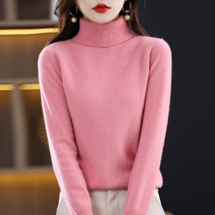 Model i lyserød rullekravesweater med armene ned langs siden, kombineret med lyse bukser. 7