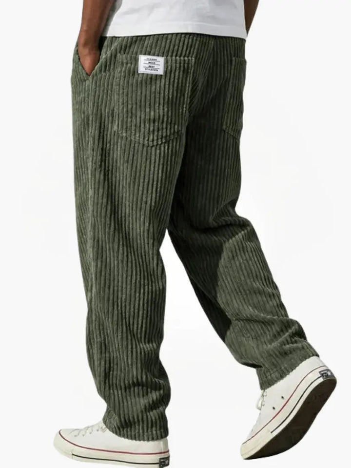 Model set bagfra i olivengrønne fløjlsbukser med afslappet pasform, baglommer og stofmærke, med hvid t-shirt og hvide sneakers. 7