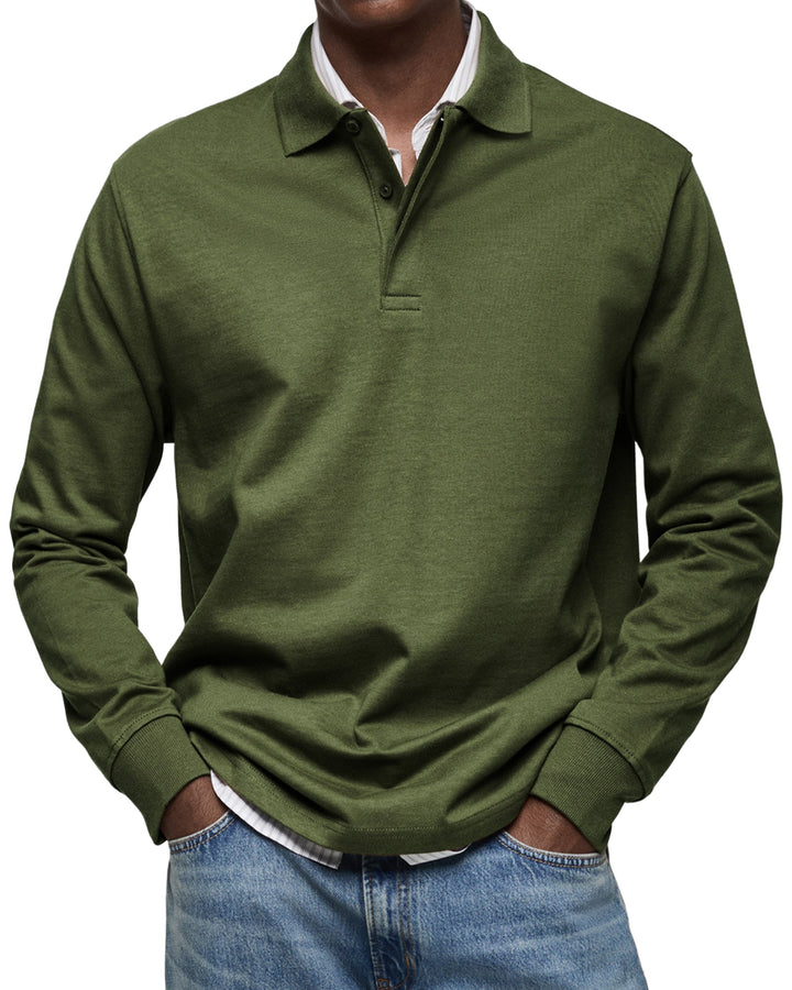 Langærmet poloshirt i mørk olivengrøn, båret af en model med stribet skjorte under og jeans, set forfra. 10