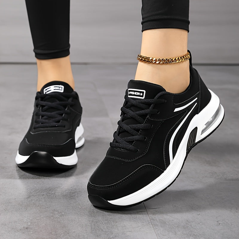 Model i sorte leggings og guldkæde om anklen viser de sorte sneakers med hvide striber set skråt forfra. 2