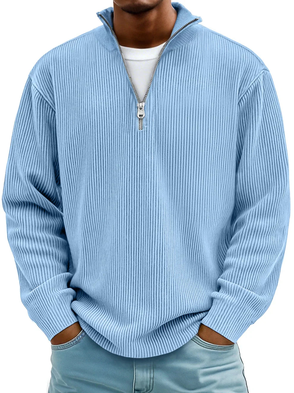 Model i lyseblå ribstrikket sweater med halv lynlås og stehylde, hænder i lommerne på jeans 1