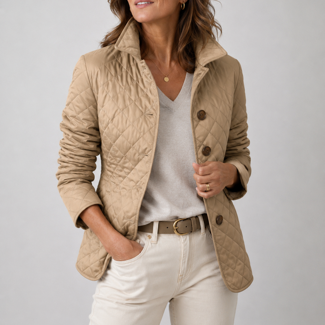 Kvinde i beige ternet jakke med brune knapper, grå V-hals trøje og lyse jeans 1