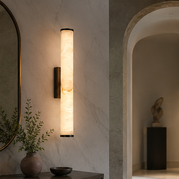 Lysende marmorlampe med sort beslag på en marmormønstret væg i en entré med buegang, spejl og vase med grene. 5