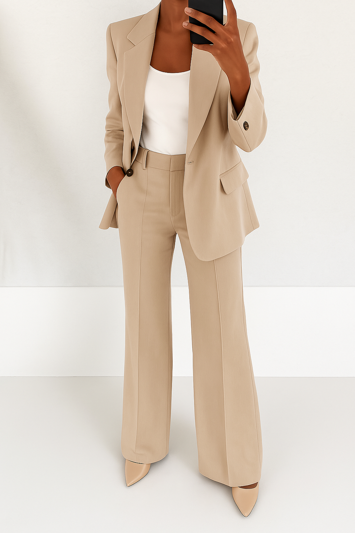 Model i beige buksedragt med hvid top og beige pumps, taget i spejlet med mobil 3