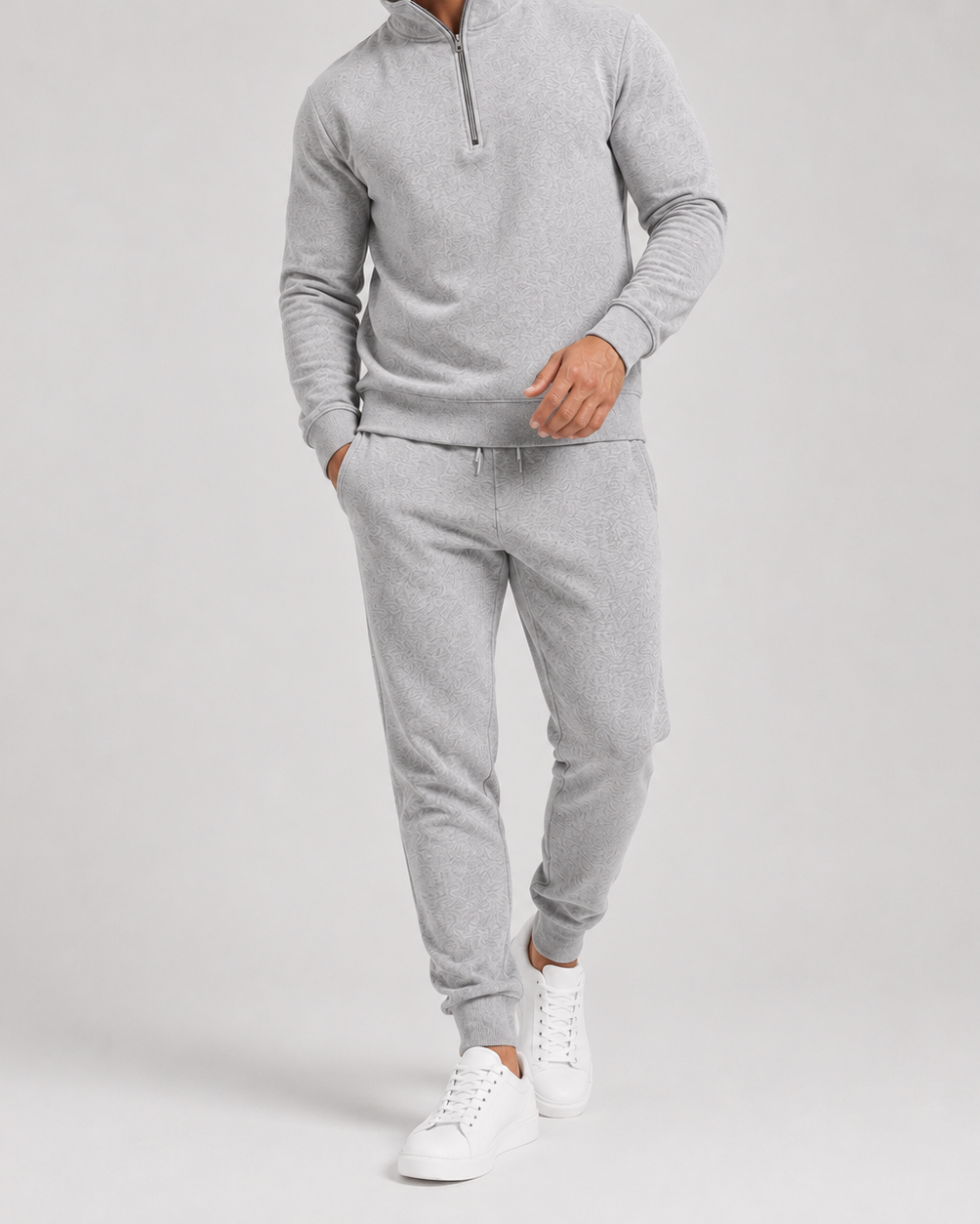 Nærbillede af den lysegrå trøje og joggingbukser med snor i taljen, båret af model 2