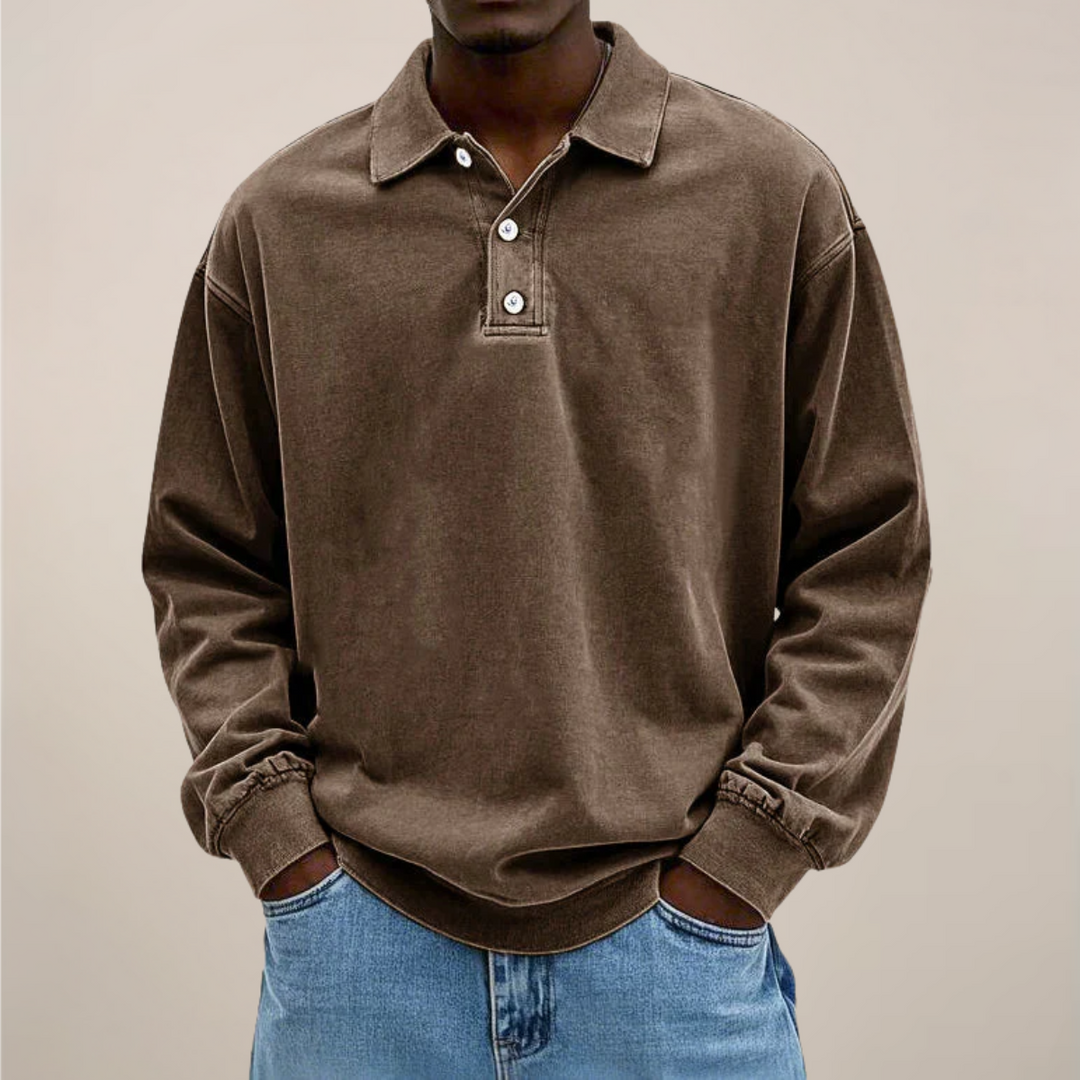 Model set forfra i brun langærmet polotrøje med krave og knaplukning, hænderne i lommerne på lyse jeans. 3