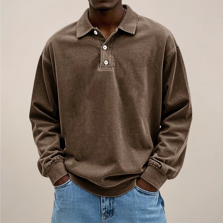 Model set forfra i brun langærmet polotrøje med krave og knaplukning, hænderne i lommerne på lyse jeans. 3