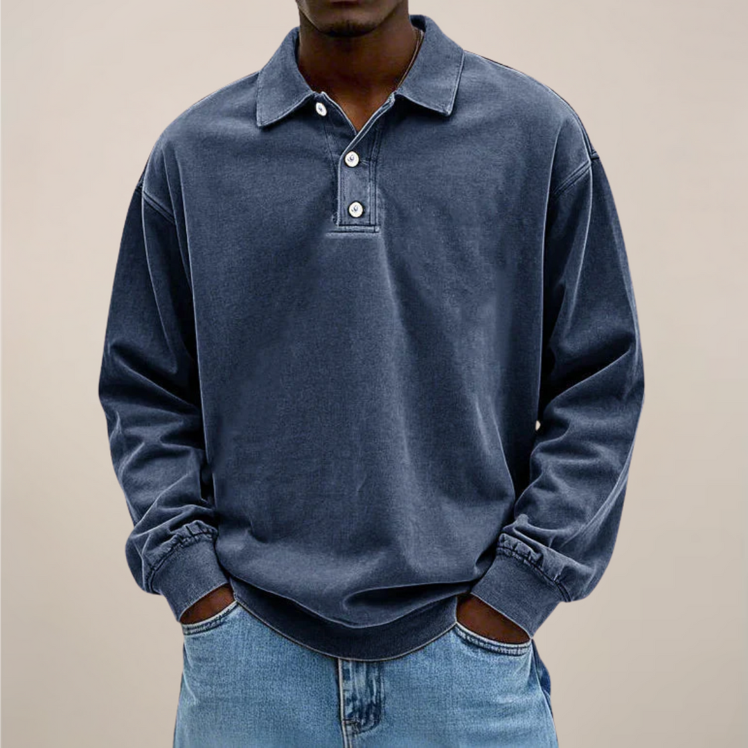 Model set forfra i mørkeblå langærmet polotrøje med afslappet pasform og ribkanter, båret til lyse jeans. 5