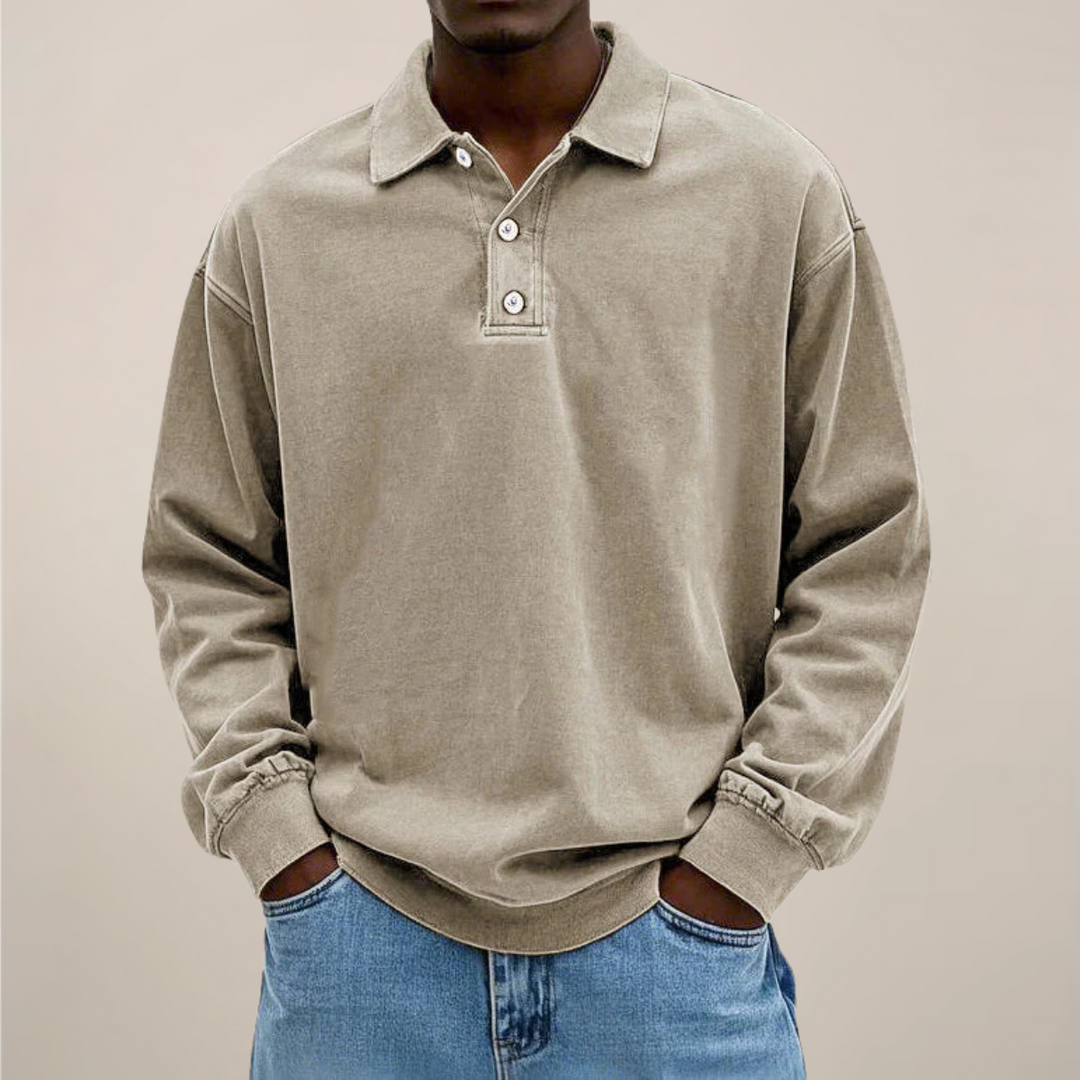 Model set forfra i beige langærmet polotrøje med knaplukning ved halsen, hænderne i lommerne på lyse jeans. 6