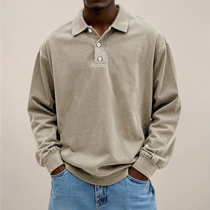 Model set forfra i beige langærmet polotrøje med knaplukning ved halsen, hænderne i lommerne på lyse jeans. 6