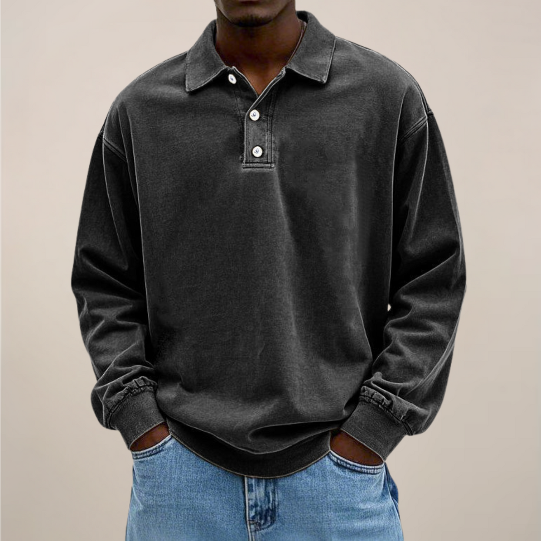 Model set forfra i sort langærmet polotrøje med krave, knaplukning og ribkant, båret til lyse jeans. 8