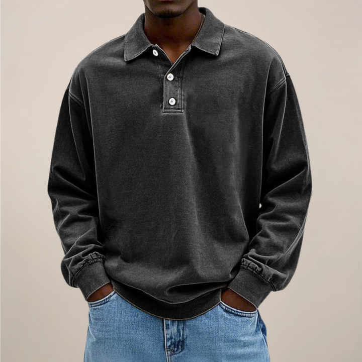 Model set forfra i sort langærmet polotrøje med krave, knaplukning og ribkant, båret til lyse jeans. 8