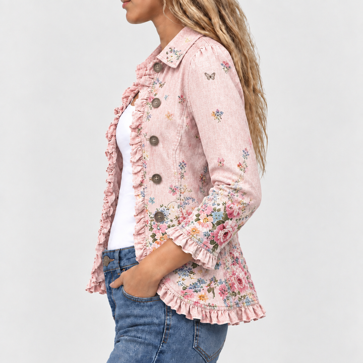 Sidebillede af jakken med knaprække, flæser langs kanten og ved ærmet samt blomsterprint, båret med hånden i jeanslommen. 3