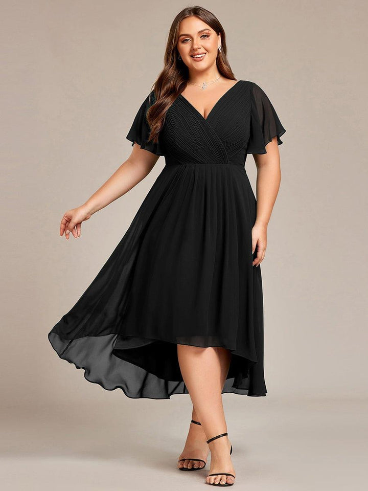 Sort kjole i plussize på model, set forfra med svingende asymmetrisk nederdel og sorte sandaler. 26