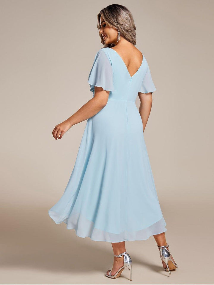 Lyseblå chiffonkjole set bagfra på plus size-model, med V-udskæring i ryggen, lynlås og bølgende fald. 90