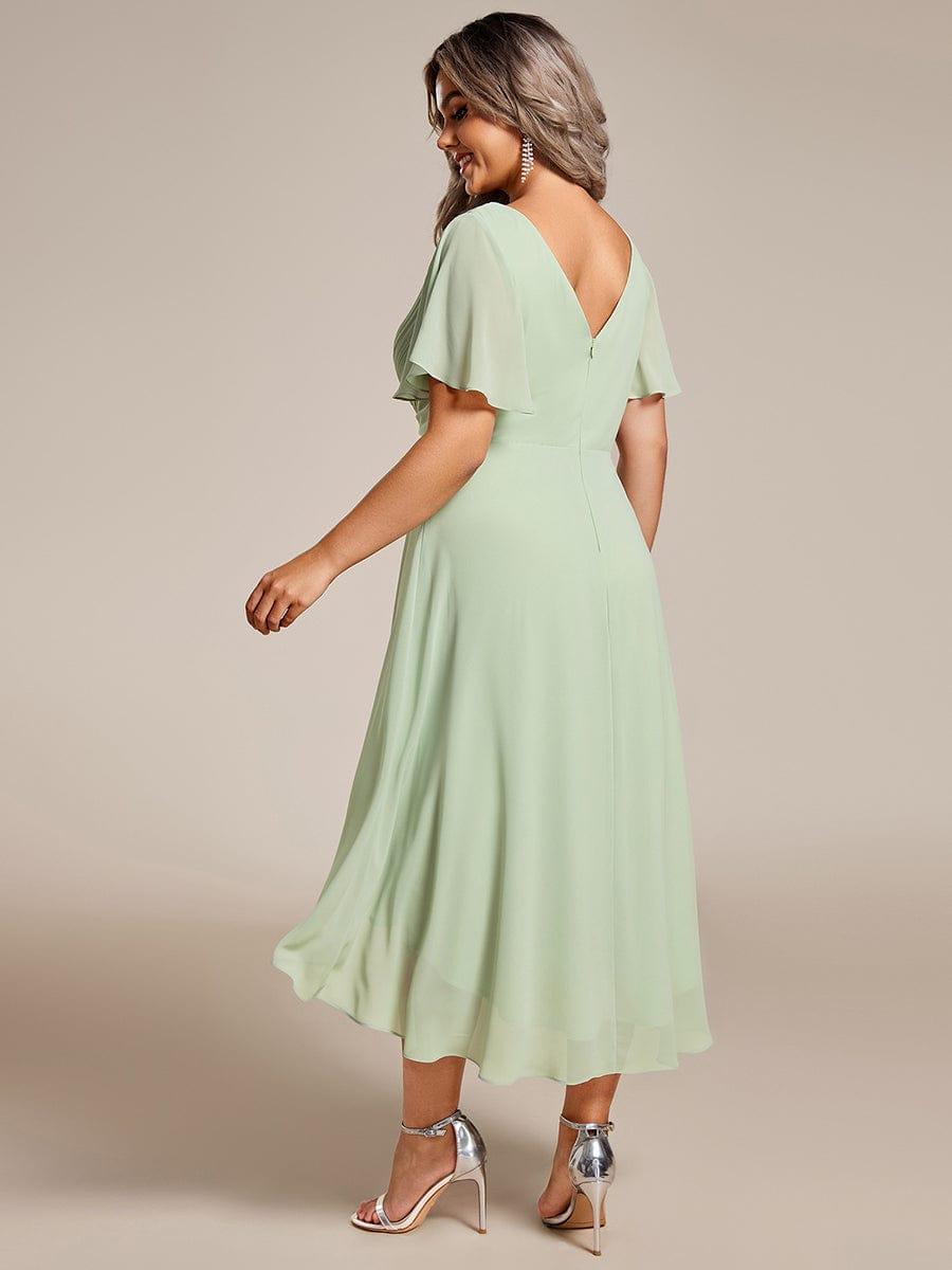 Mintgrøn chiffonkjole set bagfra på plus size-model, med dyb V-udskæring i ryggen, lynlås og flagrende korte ærmer. 82