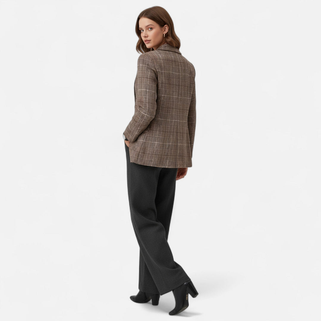 Model set bagfra og kigger over skulderen, iført den ternede blazer med grå bukser og sorte støvler med blokhæl. 3