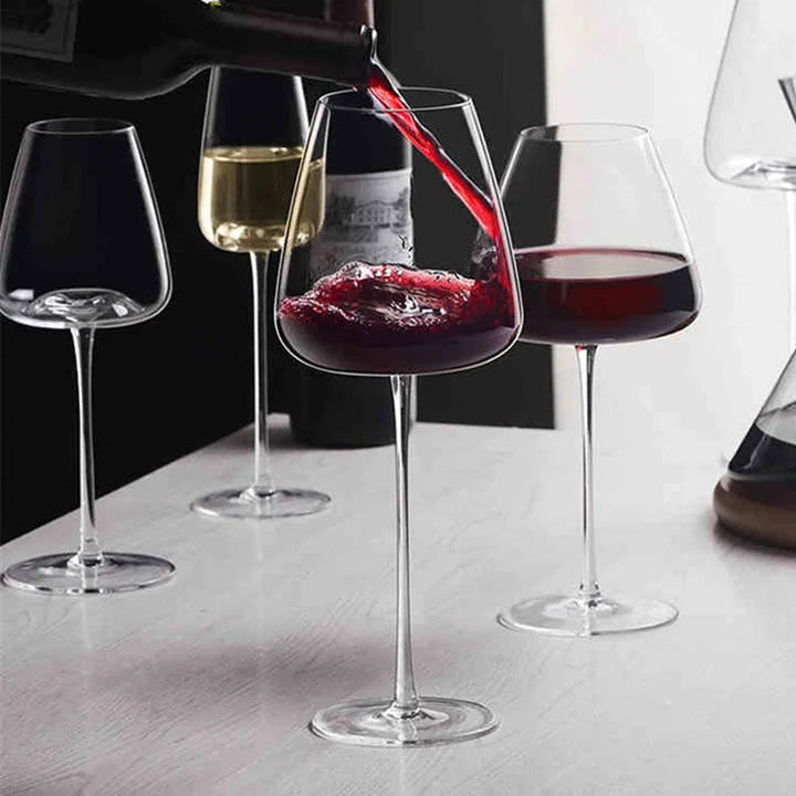 Rødvin hældes fra flasken i et glas, omgivet af glas med hvid- og rødvin 2