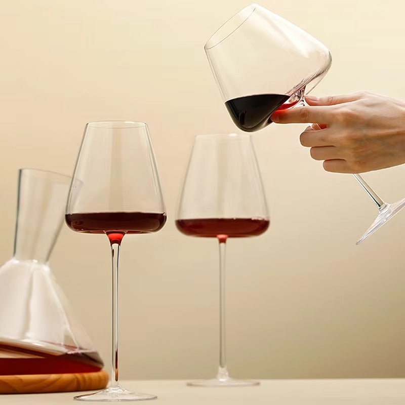 En hånd vipper et rødvinsglas, mens to andre glas og en karaffel står ved siden af 9