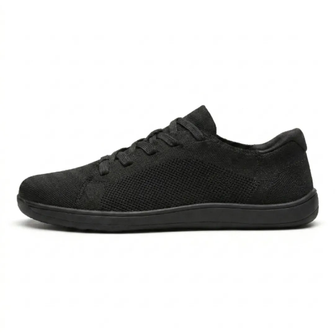 Sort sneaker i åndbart strikmesh med sort flad sål, set fra siden på hvid baggrund. 10