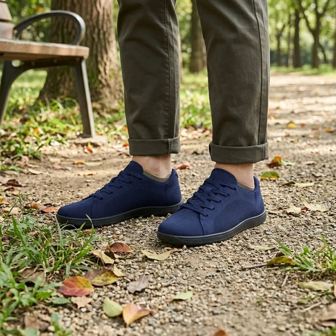 Mørkeblå strikmesh-sneakers med sort sål båret af en person i olivengrønne bukser ved en parkbænk. 20