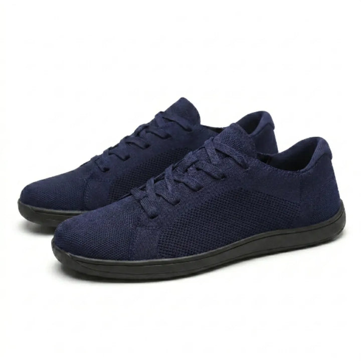 Par marineblå mesh-sneakers med snørebånd og sort sål set skråt forfra mod hvid baggrund. 25