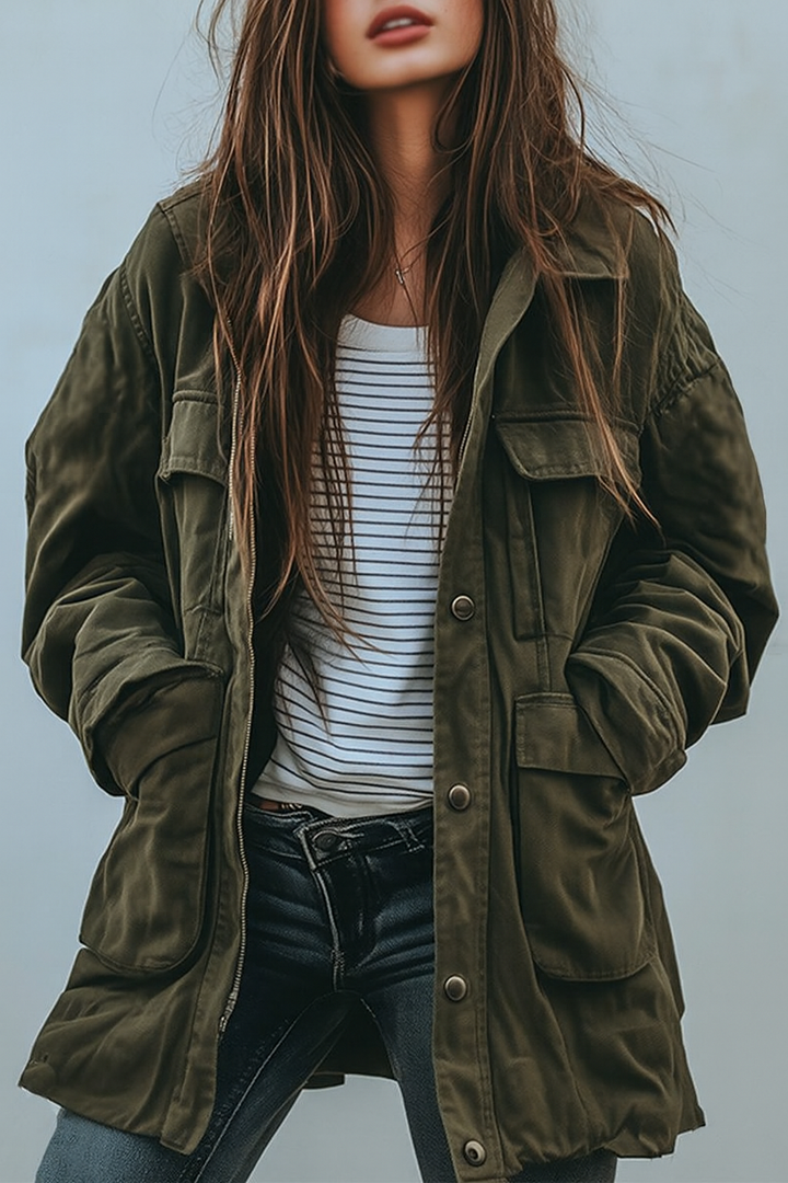 Model med langt hår bærer den åbne olivengrønne jakke med store lommer over stribet t-shirt og mørke jeans, set forfra. 1