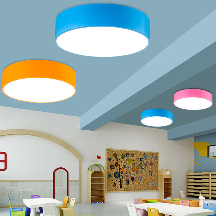 Runde loftlamper i blå, orange og pink i et lyst børneværelse med legemøbler og opslagstavle 4