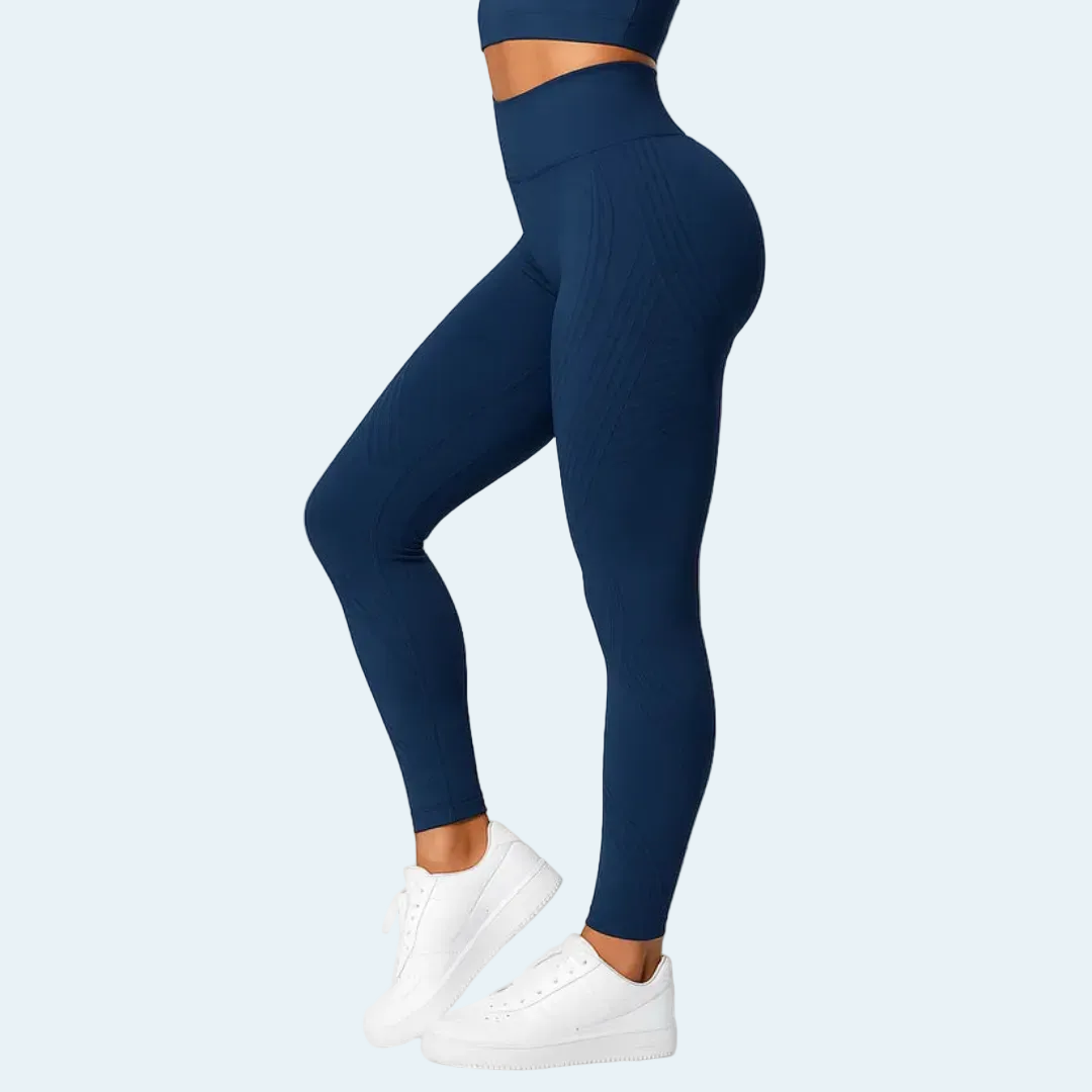 Model i marineblå højtaljede leggings med matchende top set fra siden, båret med hvide sneakers. 4