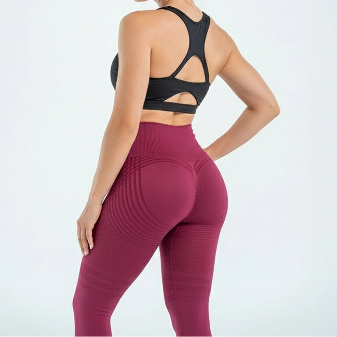 Model set bagfra i vinrøde leggings med buede striber over baller og lår, kombineret med sort sports-bh. 6
