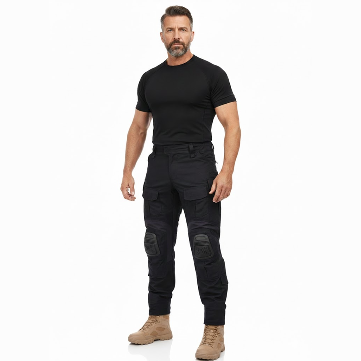 Fuld figur af mand i sort T-shirt og beige støvler iført de sorte cargobukser med lårlommer og knæbeskyttere. 7