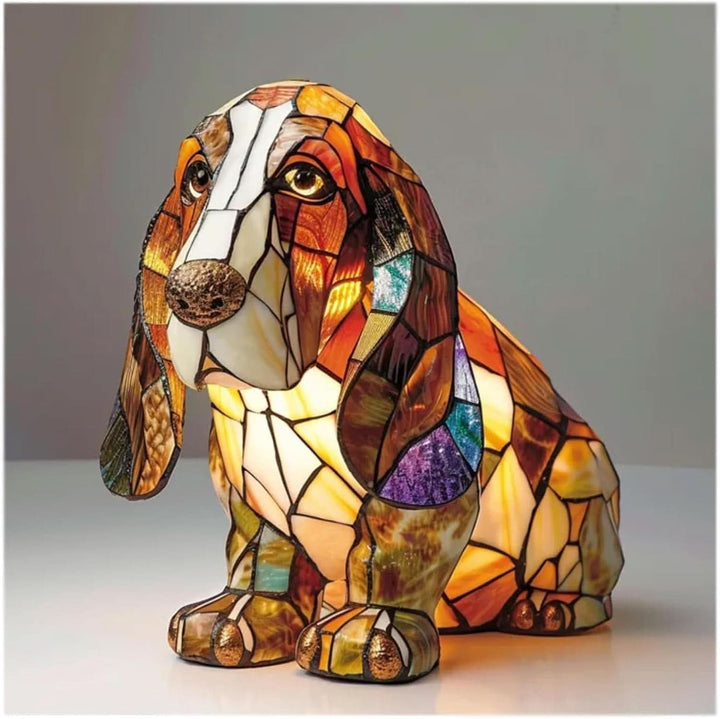 Siddende basset hound-lampe med lange hængende ører i mosaikmønster, tændt og med varmt lys på hvid overflade. 2