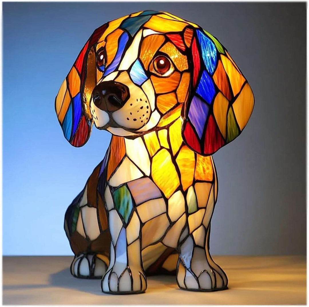 Siddende beagle-lampe med farvet mosaikglas-look i orange, hvid og blå, tændt mod blå baggrund og set forfra. 1
